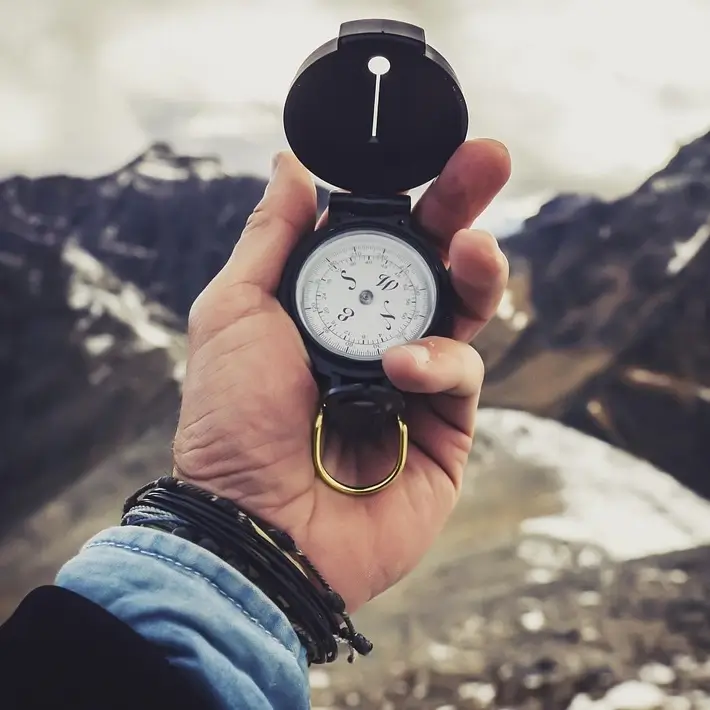 Une boussole tenue dans la main devant des montagnes