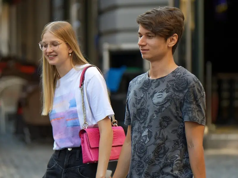 Une jeune homme et une jeune femme marchent ensemble et semble être timides.