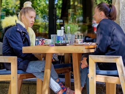 Deux femmes assises sur une terrasse discutent.