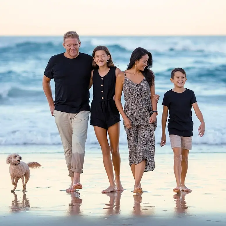 Un père, une mère et 2 enfants marchent sur la plage