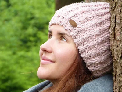Une jeune fille en hiver regarde le ciel avec contentement.