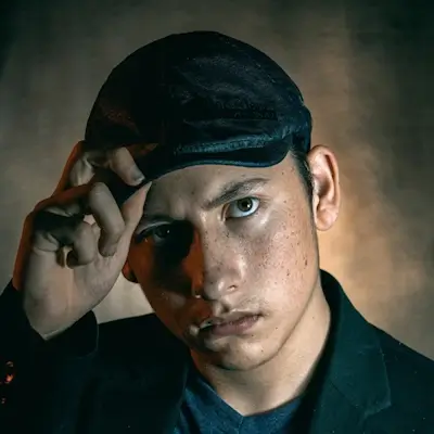 Un jeune homme irrité salut en mettant la main sur son chapeau