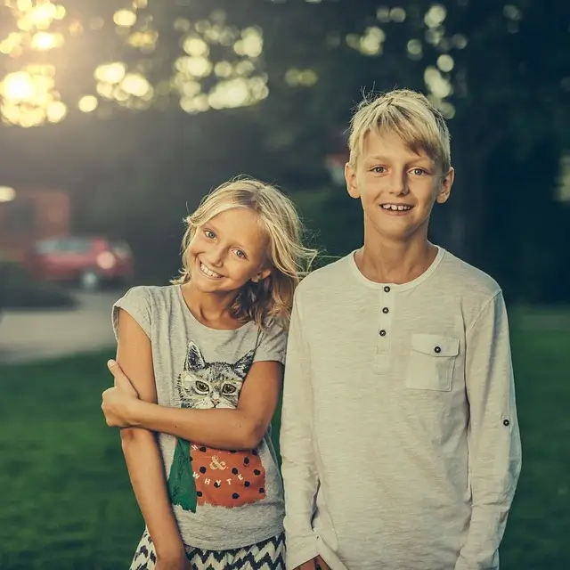 Deux enfant debout sur le gazon sourient