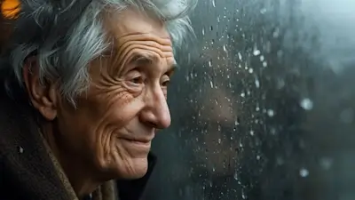 Un vieillard souriant regarde la pluie tomber