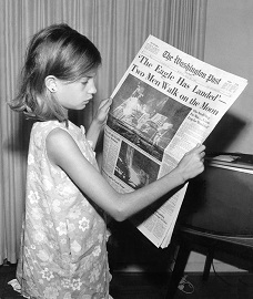 Fillette qui tient dans ses mains un journal.
