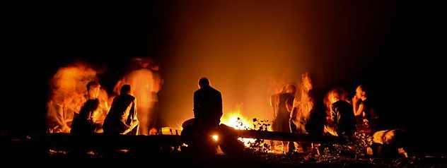 Une personne seule dans un groupe près d’un feu de camp.