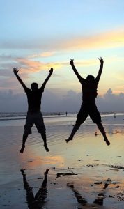 Deux hommes sautent de joie devant le soleil.