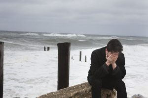 Homme triste devant une mer agitée