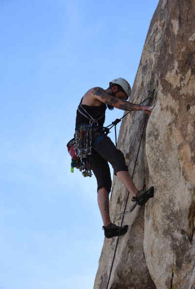 Un individu escalade un massif rocheux vertical.