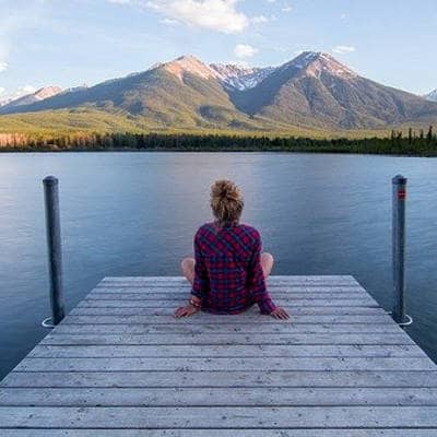 Une femme assise sur un quai devant un lac magnifique
