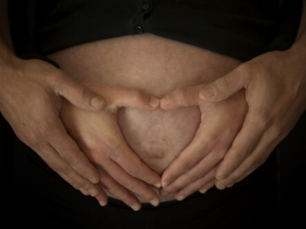 Les mains d’un homme sur le ventre d’une femme enceinte.