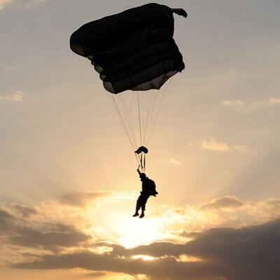 Un parachutiste décent, voile ouverte, devant le soleil