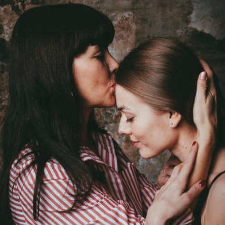 Une dame embrasse tendrement une jeune fille sur le front.