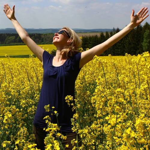 Une femme exprime sa gratitude et son bonheur en levant les bras.