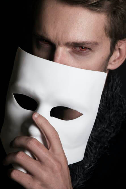 Un jeune homme au regard douteux retire un masque de théâtre.