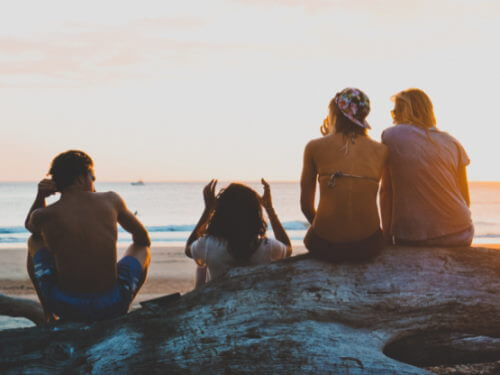 Quatre jeunes gens assis sur un plage.