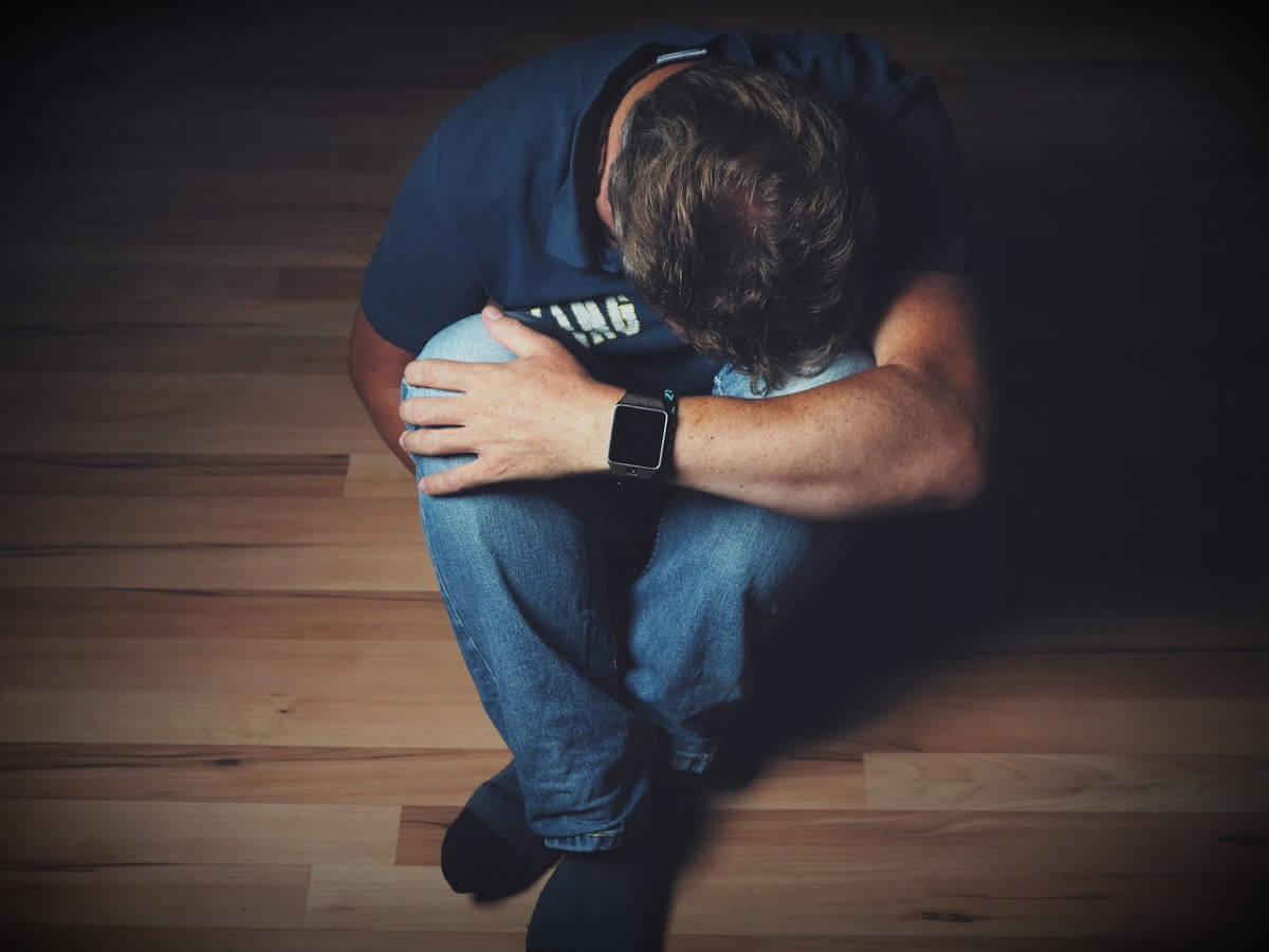 Un jeune homme déprimé cache son visage triste avec ses bras.