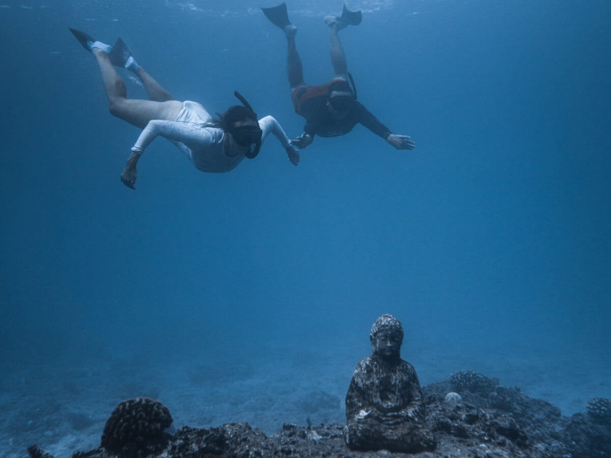 Des plongeurs découvrent une statue sous l’eau.