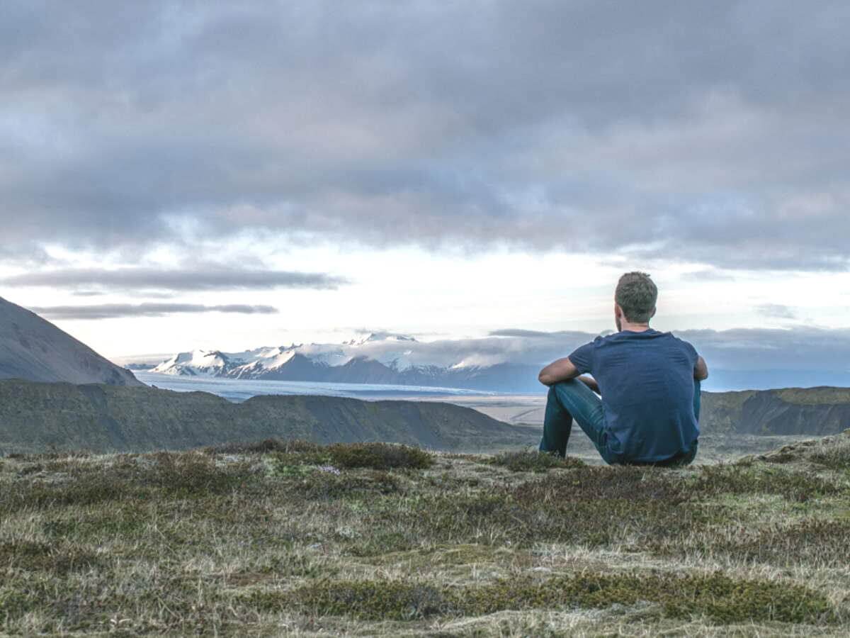Un jeune homme seul admire un paysage montagneux.