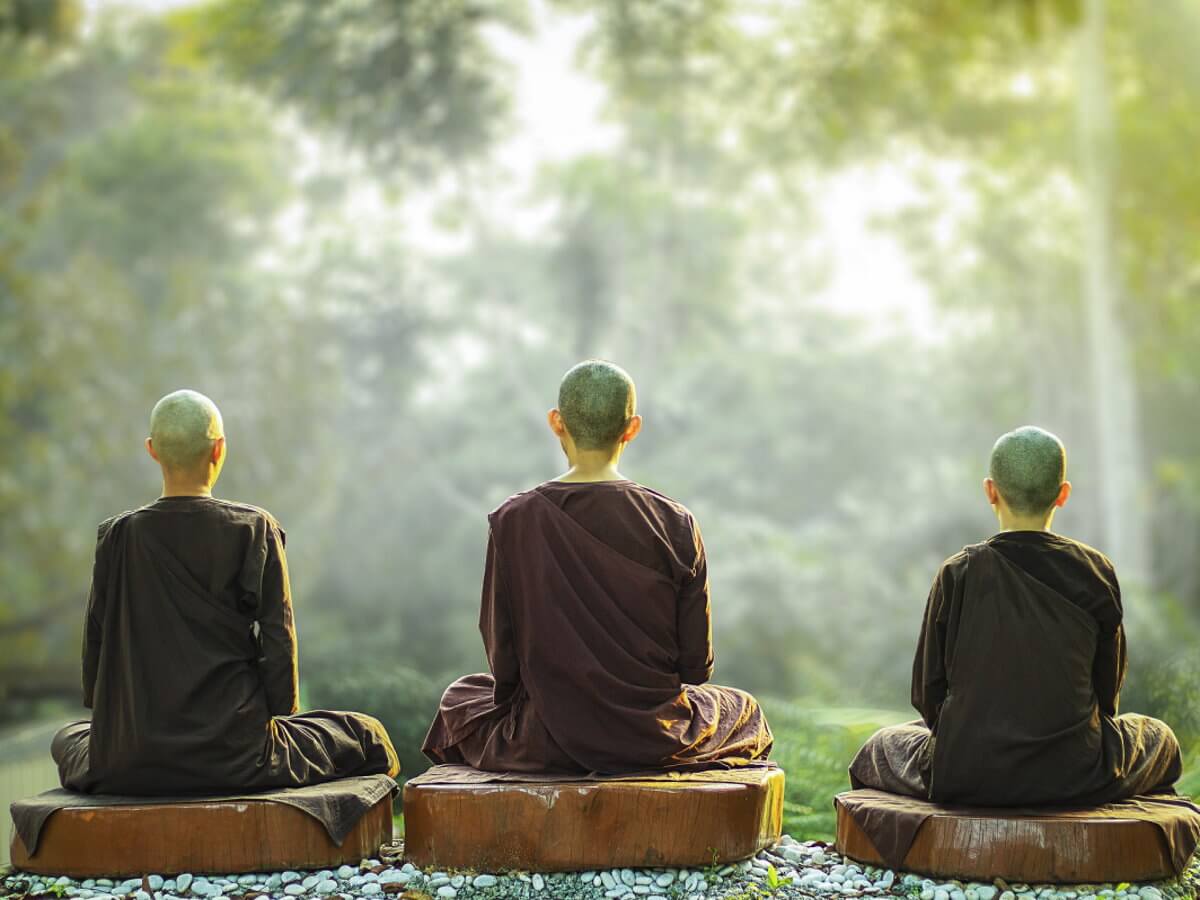 Trois moines assis en position de méditation