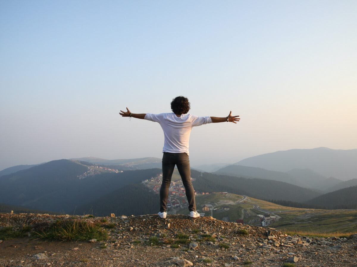 Sur une colline, un homme a les bras en croix.