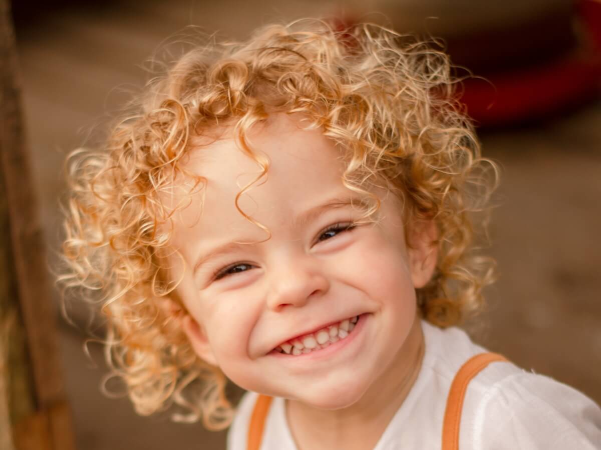 Un enfant de 5 ans sourit largement.