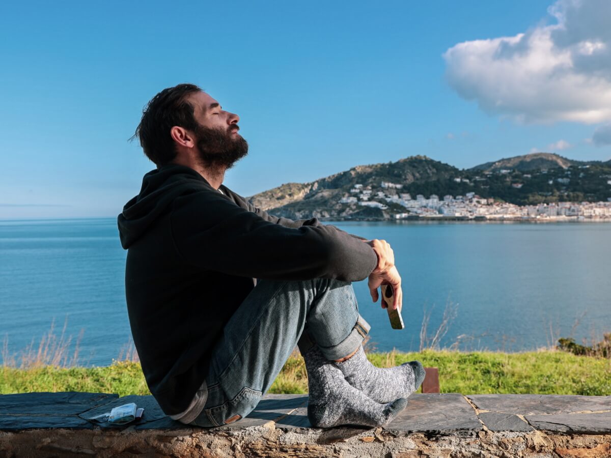 Un jeune homme médite assis parterre les yeux fermés.