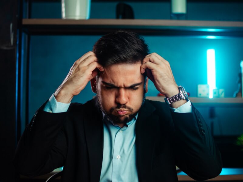 Un homme stressé met les mains sur sa tête.