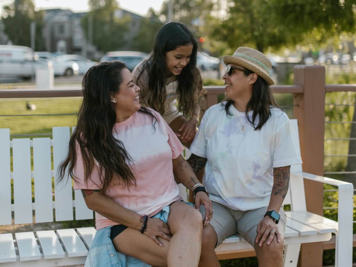 Trois femmes (2 adules et un jeune fille) se sourient.