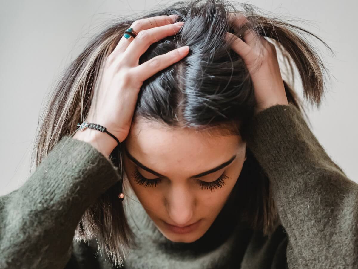 Une femme triste met les mains sur sa tête.