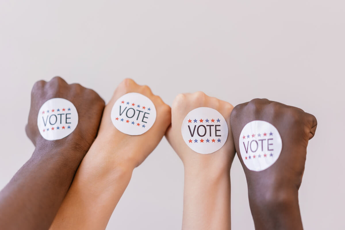 Quatre mains sur lesquelles est écrit le mot : Vote.