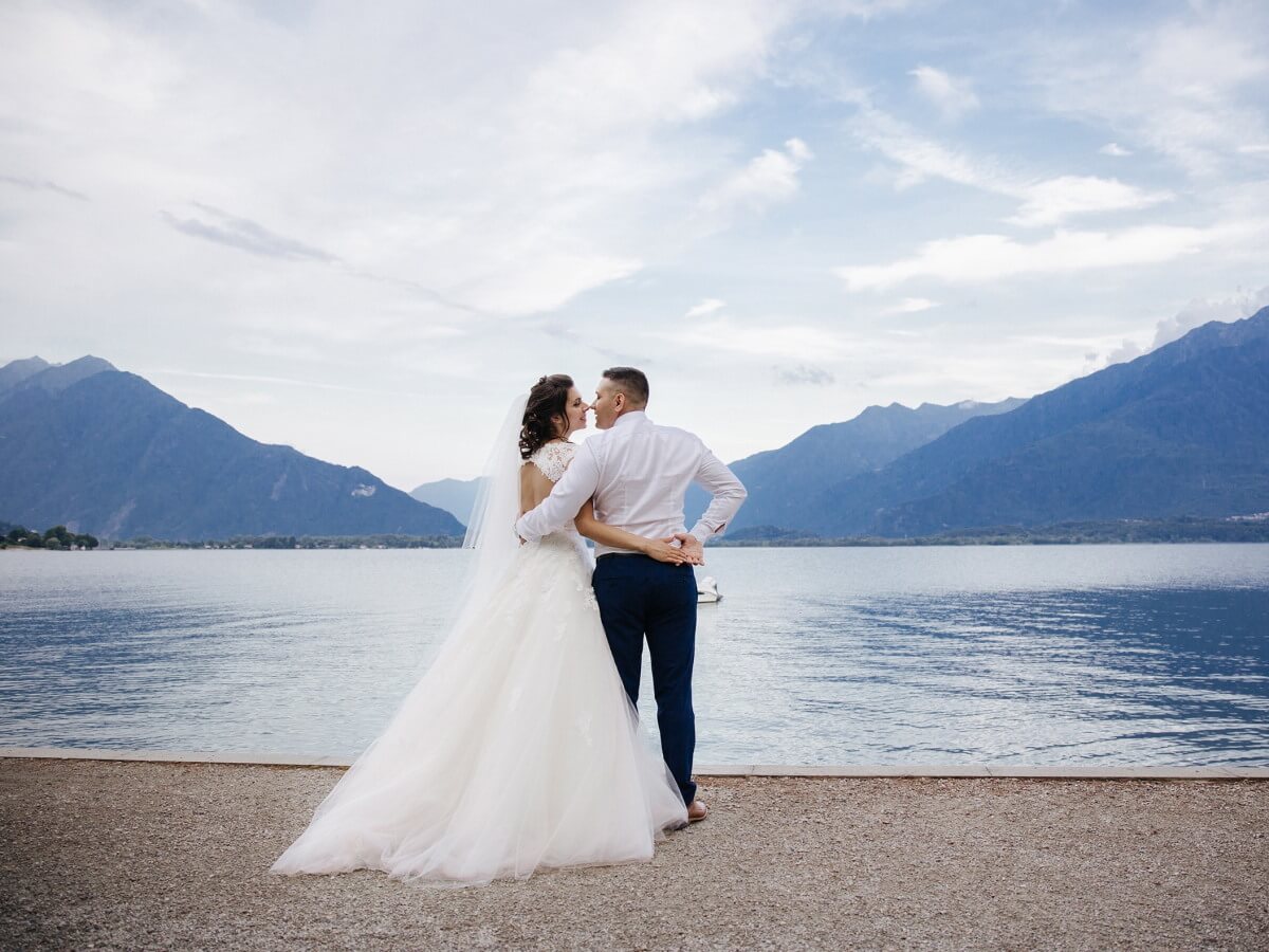 Des mariés s'embrassent devant un magnifique lac.