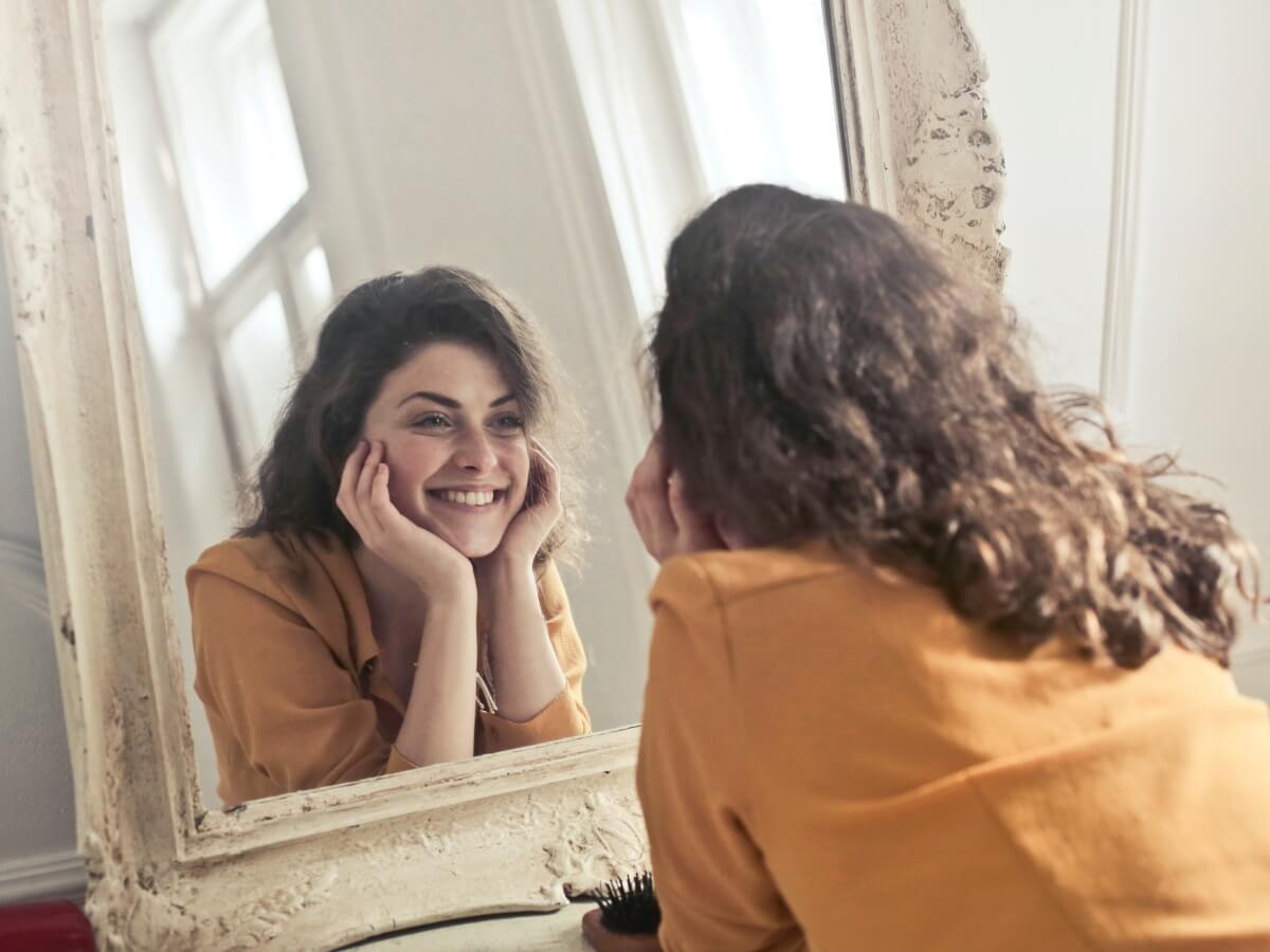 Une jeune fille se sourit à elle-même dans un miroir.