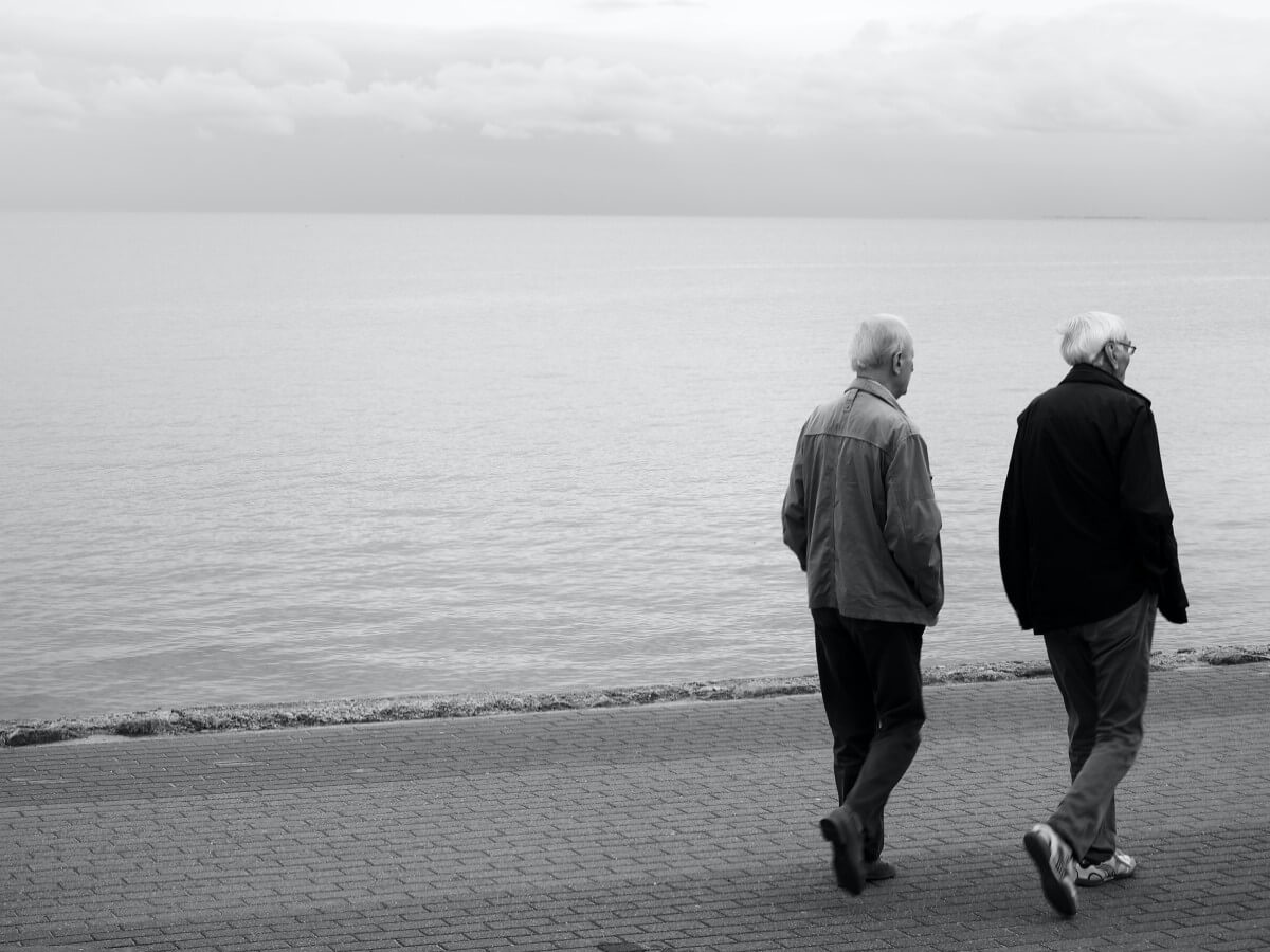 Deux hommes aux cheveux gris marchent ensemble.