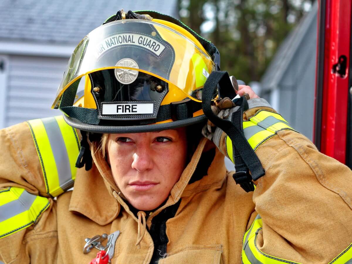Une femme pompier met son casque.