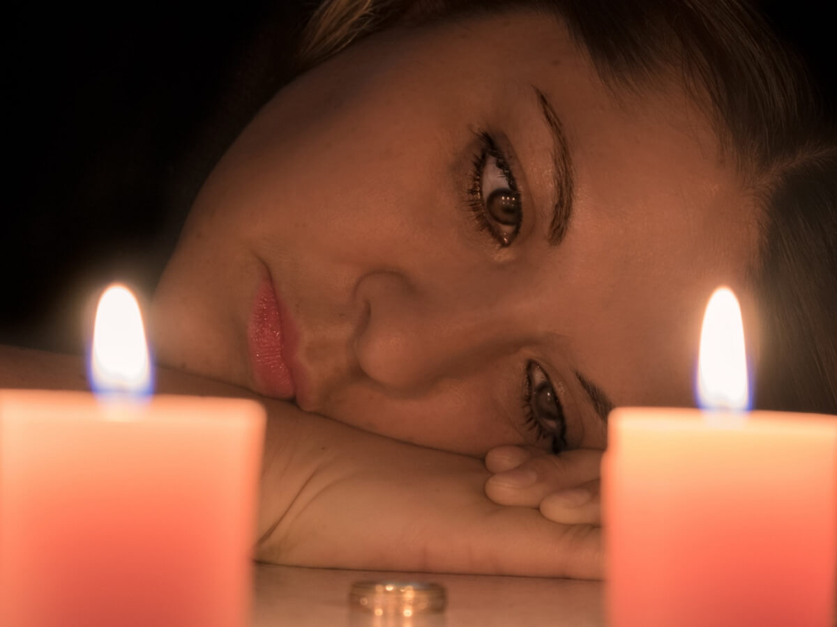 Une jeune dame pleure devant une flame.