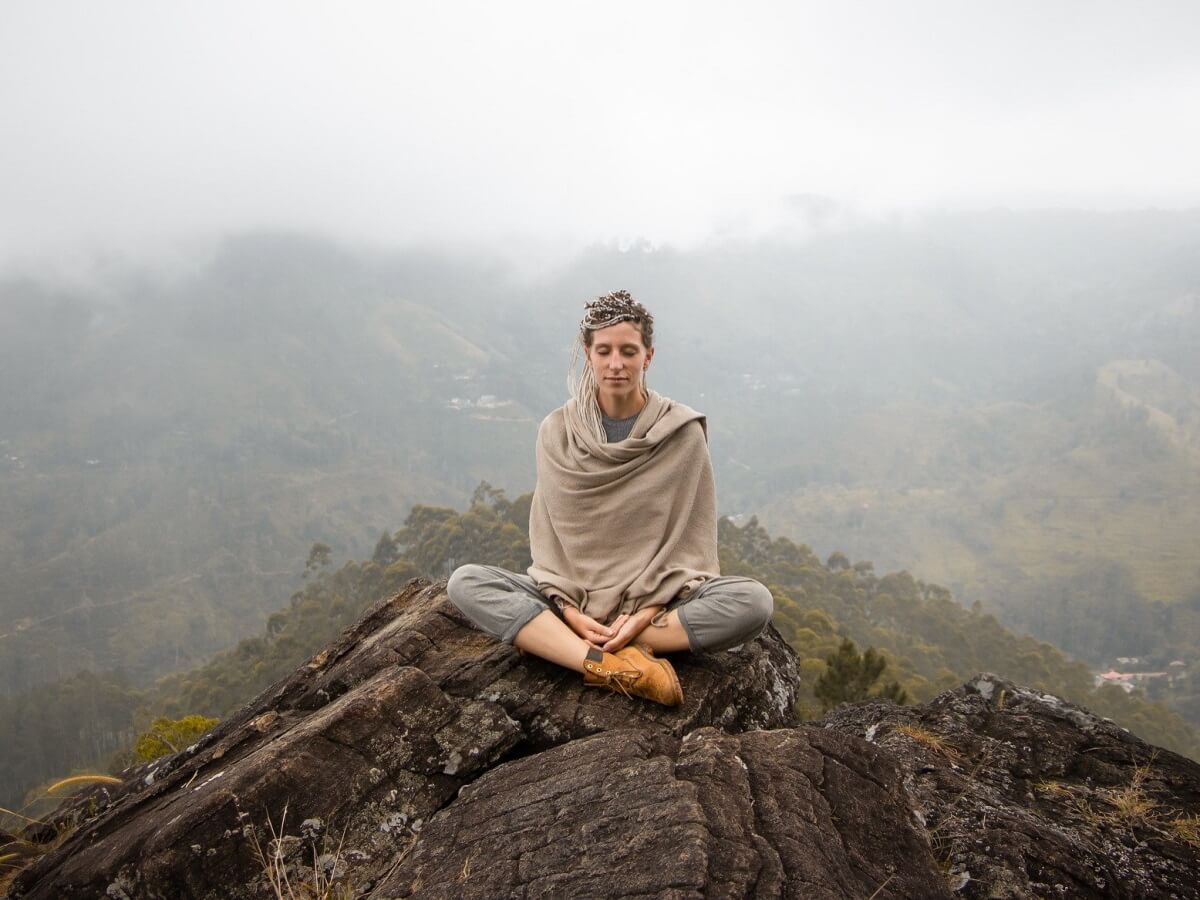 Une jeune femme en médite sur une montagne.