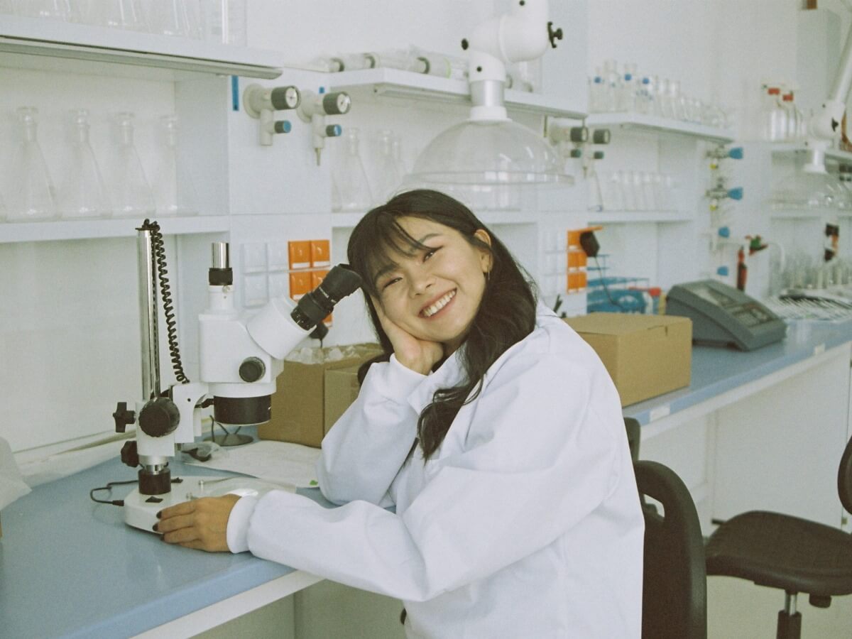 Une dame dans un laboratoire sourit largement.