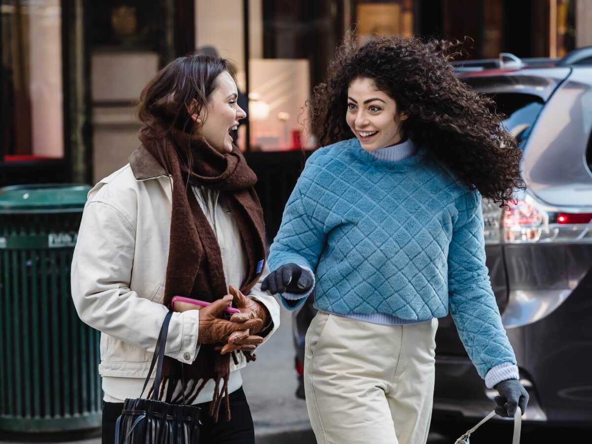 Deux femmes parlent en traversant une rue.