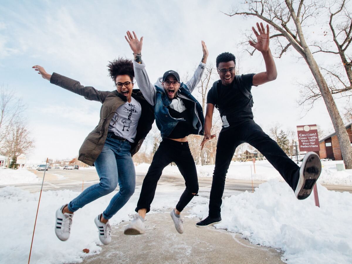 Trois jeunes personnes sautent d’enthousiasme.