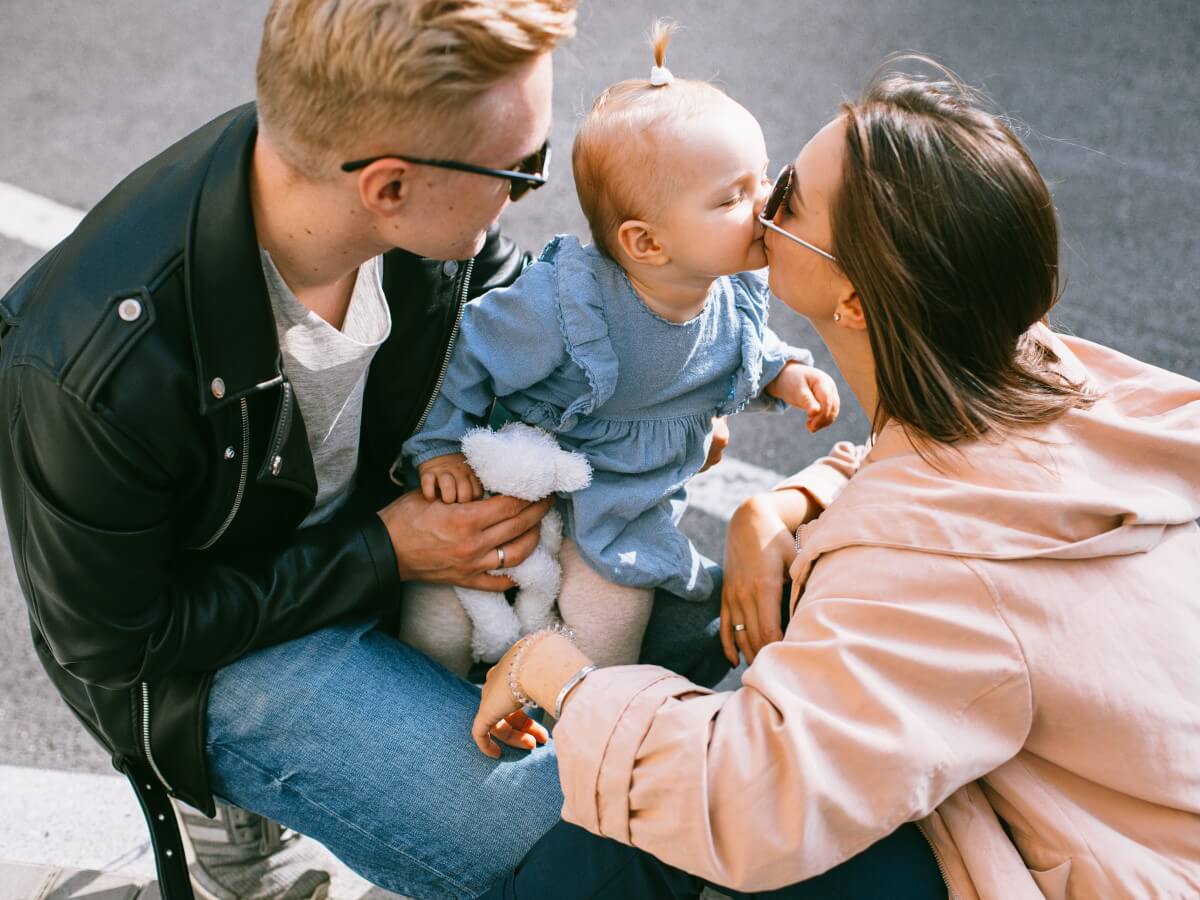 Un bébé, dans les bras de ses parents, embrasse sa mère.