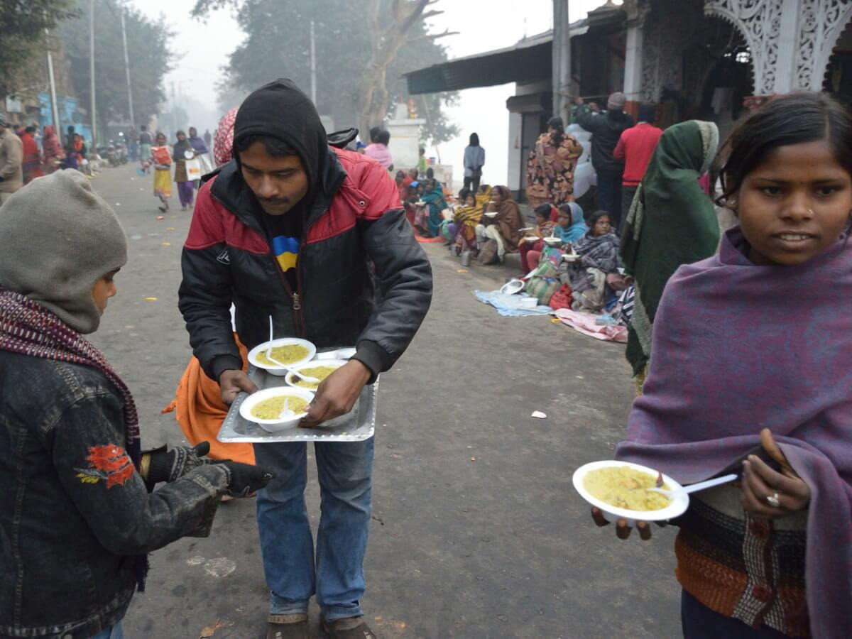 Un homme distribue de la soupe à des enfants pauvres.