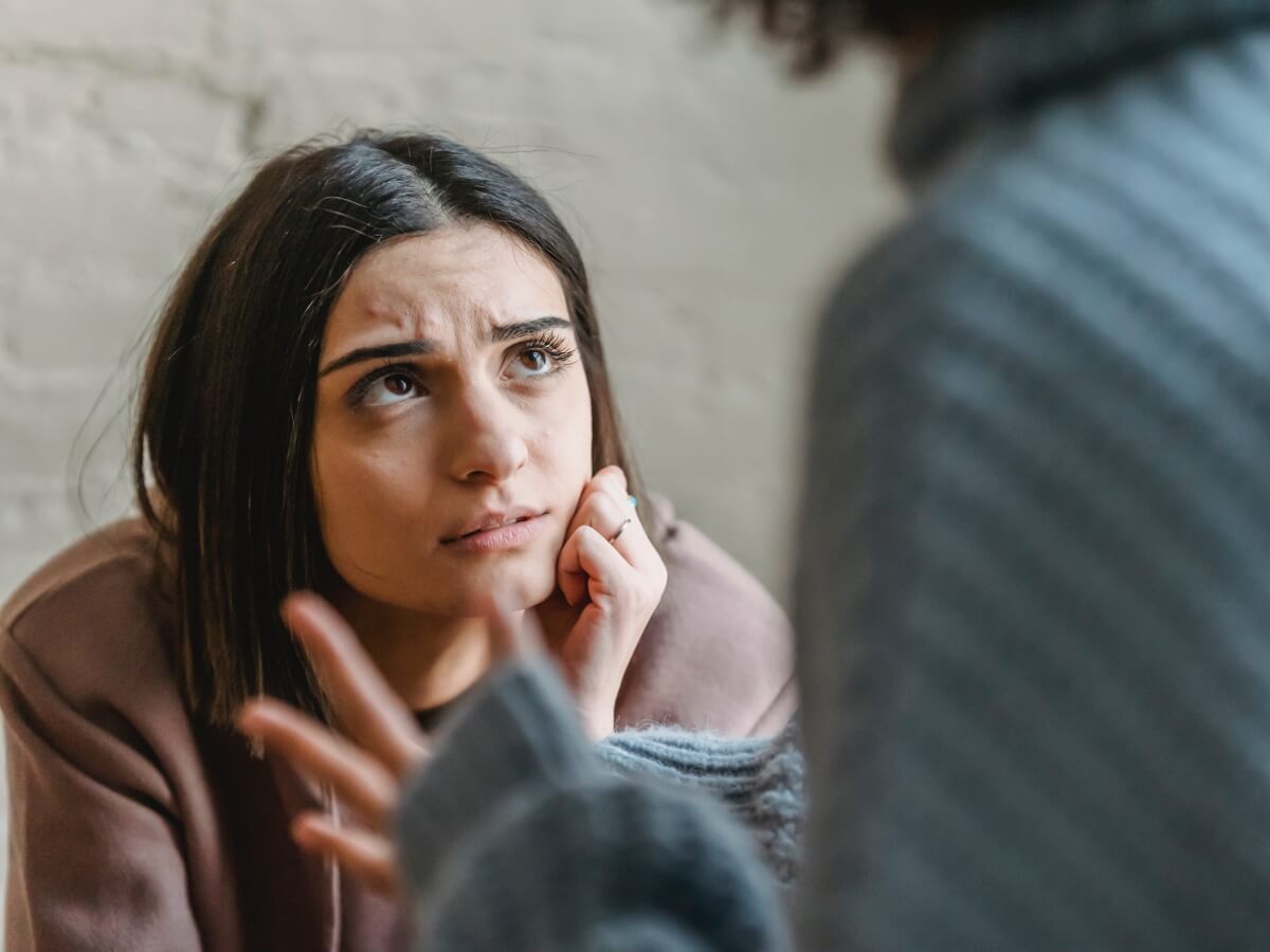 Une jeune femme offensée écoute quelqu'un lui parler.
