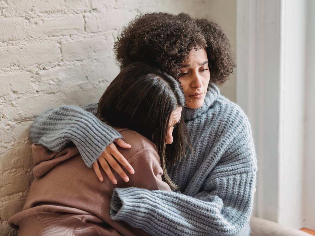 Une femme prend une jeune personne dans ses bras.