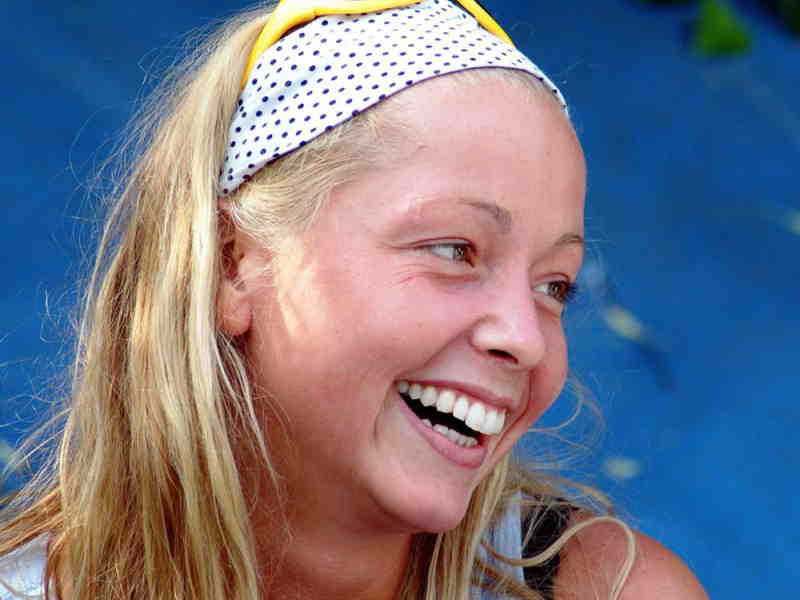 Une jeune femme blonde rit aux éclats.