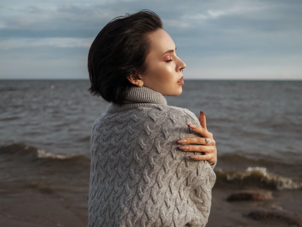 Une jeune femme pensive seule devant l’océan