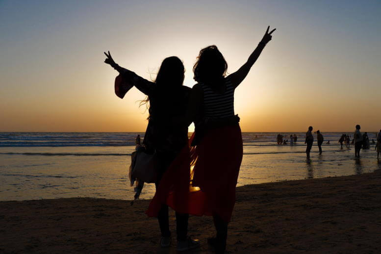 Deux femmes enlacées sur la plage devant un coucher de soleil