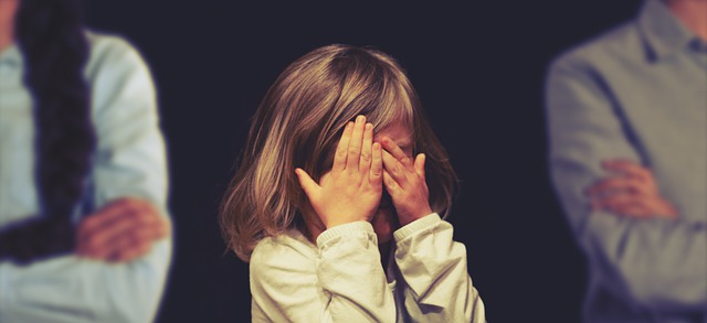 Une gamine cache son visage avec ses 2 mains.