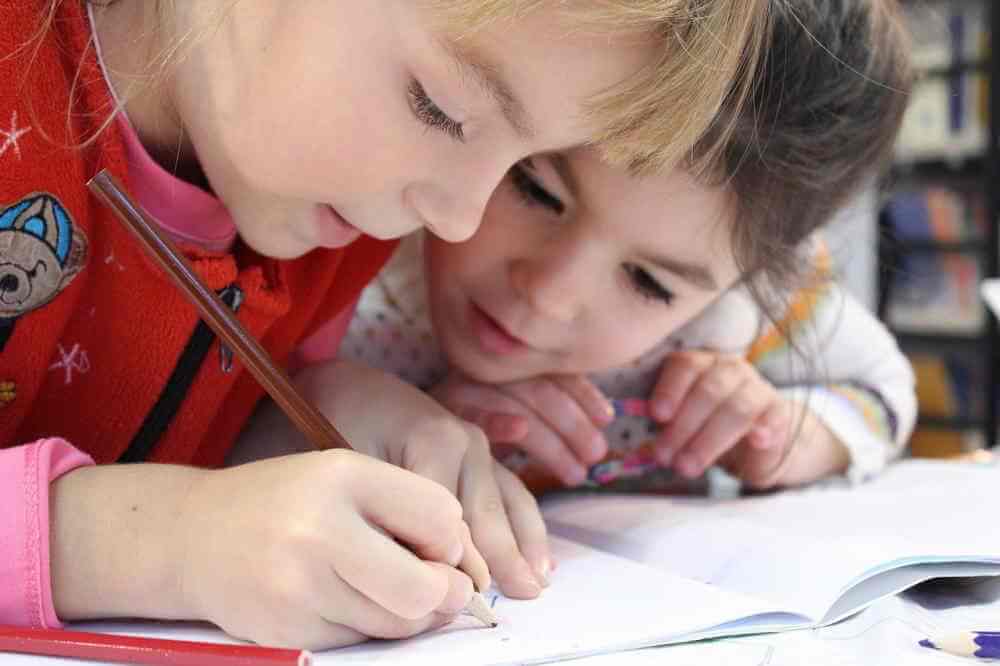 Deux fillettes dessinent au crayon.