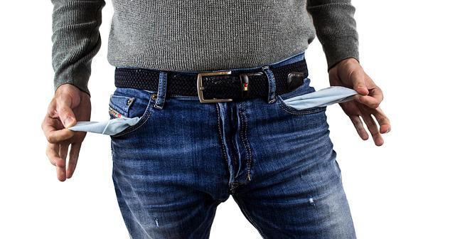 Un homme reverse ses poches de pantalon vides.